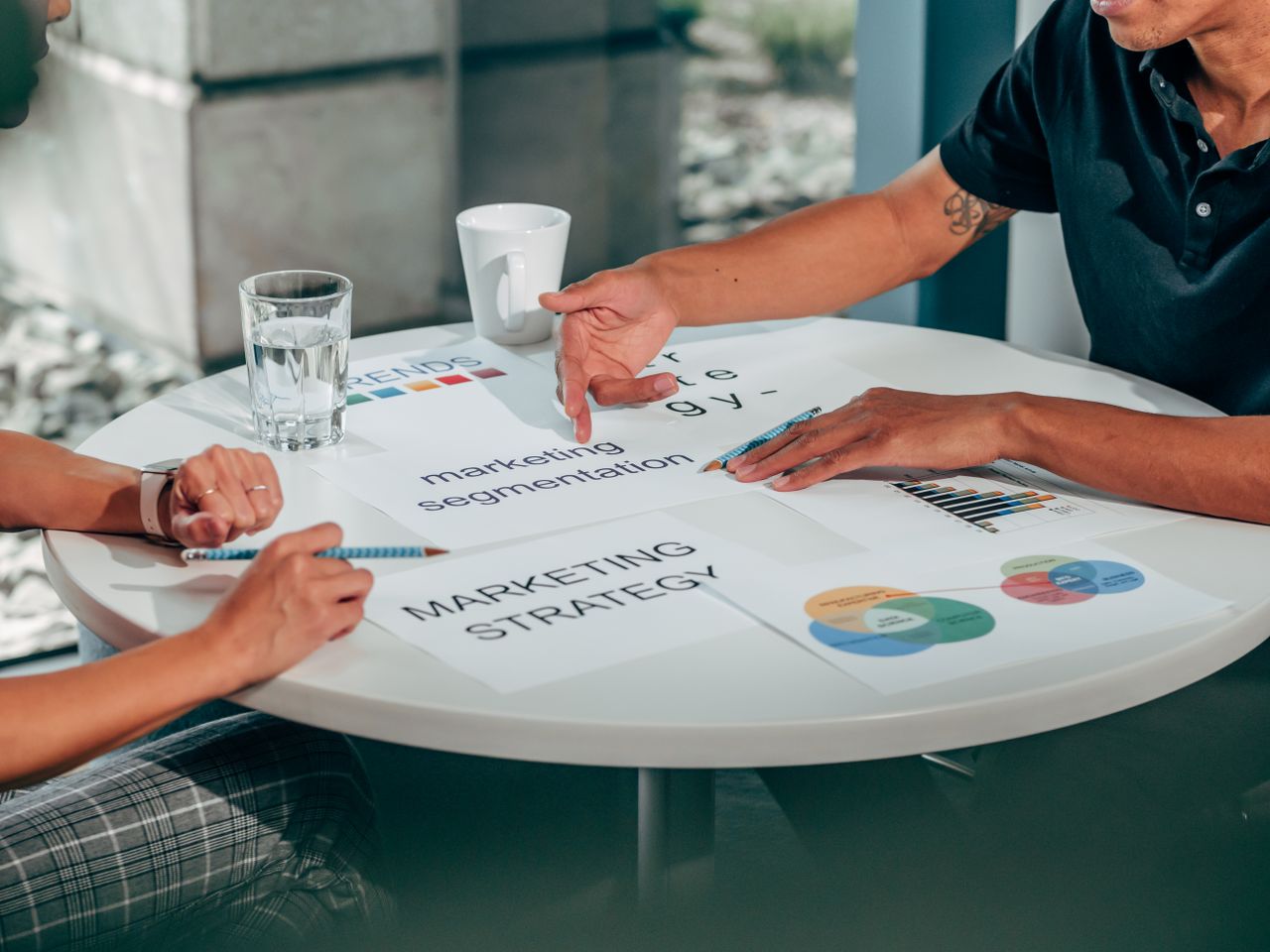 Two adults in an office talking over marketing strategy at a round table.